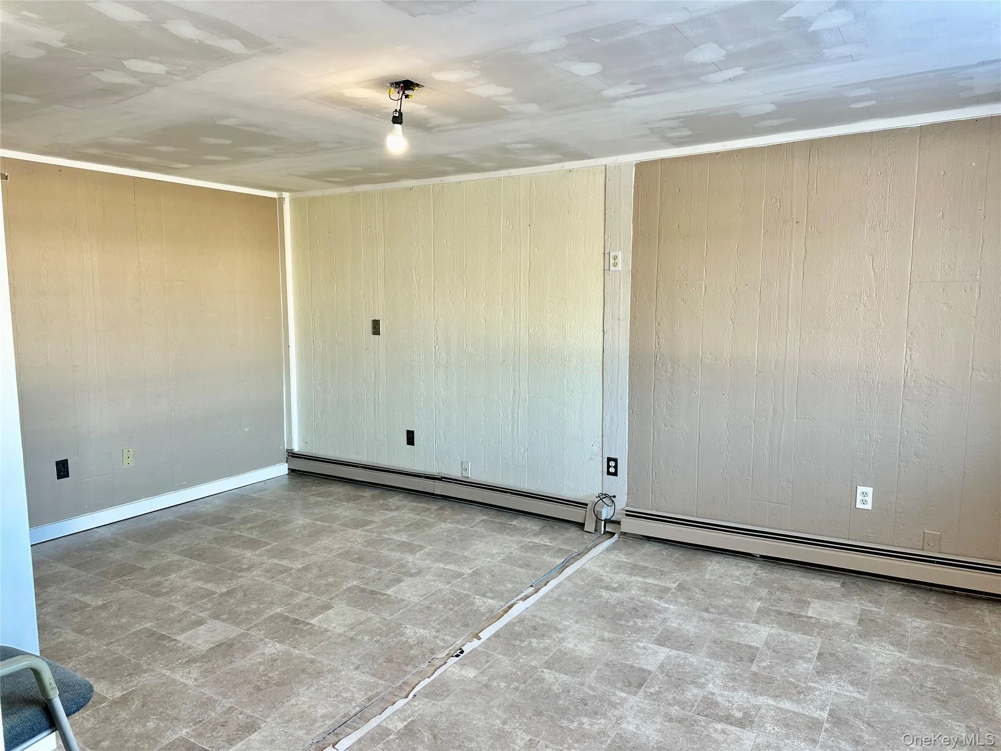 Spare room with wood walls and baseboard heating Spare room with wood walls and baseboard heating
