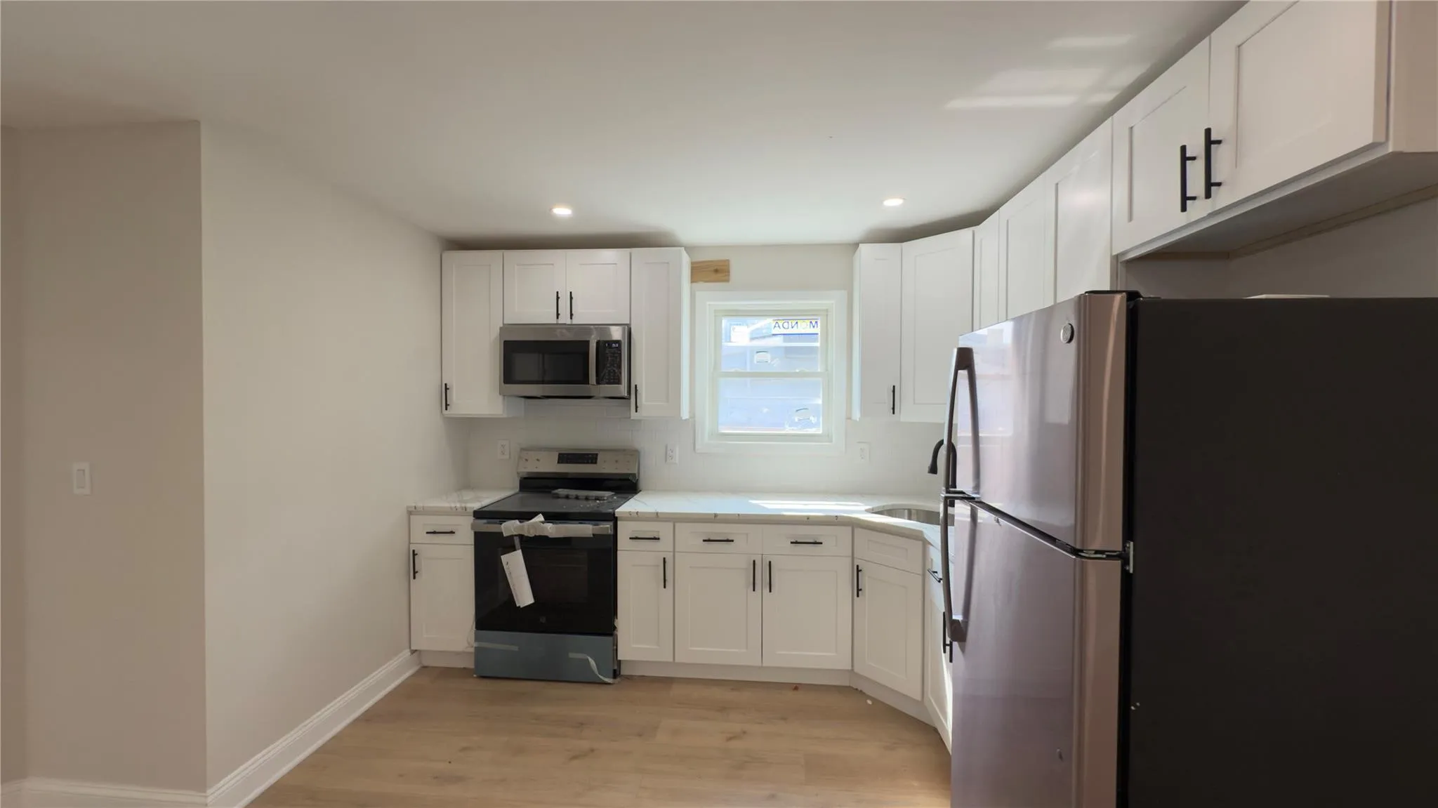 Kitchen featuring stainless steel appliances, light wood-style floors, recessed lighting, white cabinetry, and light countertops Kitchen featuring stainless steel appliances, light wood-style floors, recessed lighting, white cabinetry, and light countertops