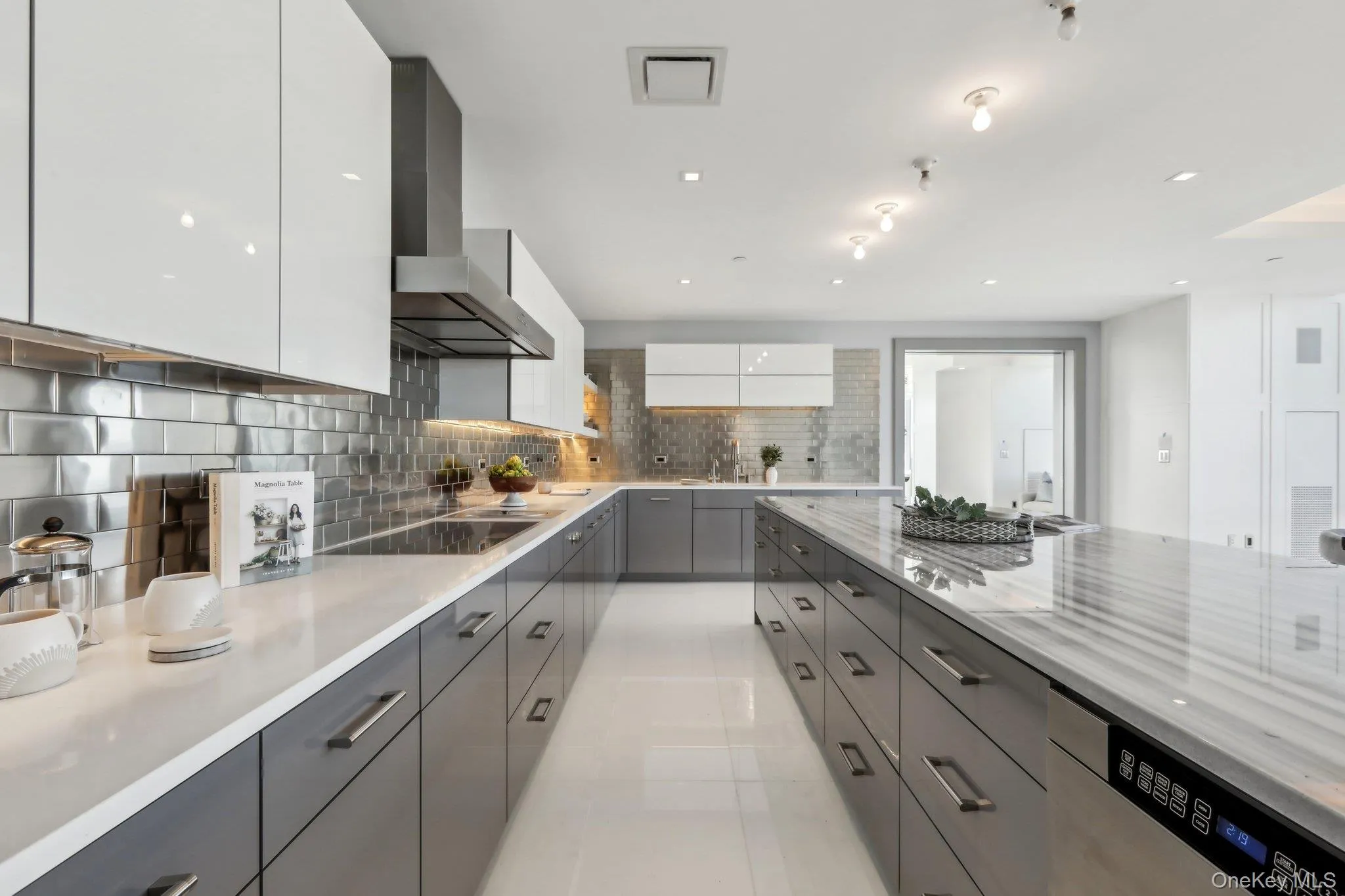 Kitchen featuring modern cabinets, black electric cooktop, gray cabinets, wall chimney range hood, and stainless steel dishwasher Kitchen featuring modern cabinets, black electric cooktop, gray cabinets, wall chimney range hood, and stainless steel dishwasher