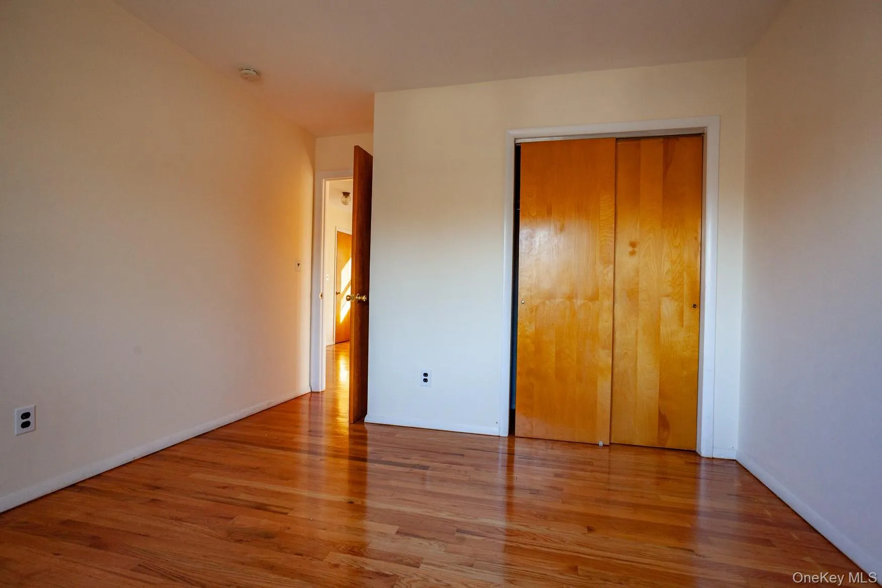 Unfurnished bedroom featuring hardwood floors and a closet. Unfurnished bedroom featuring hardwood floors and a closet.