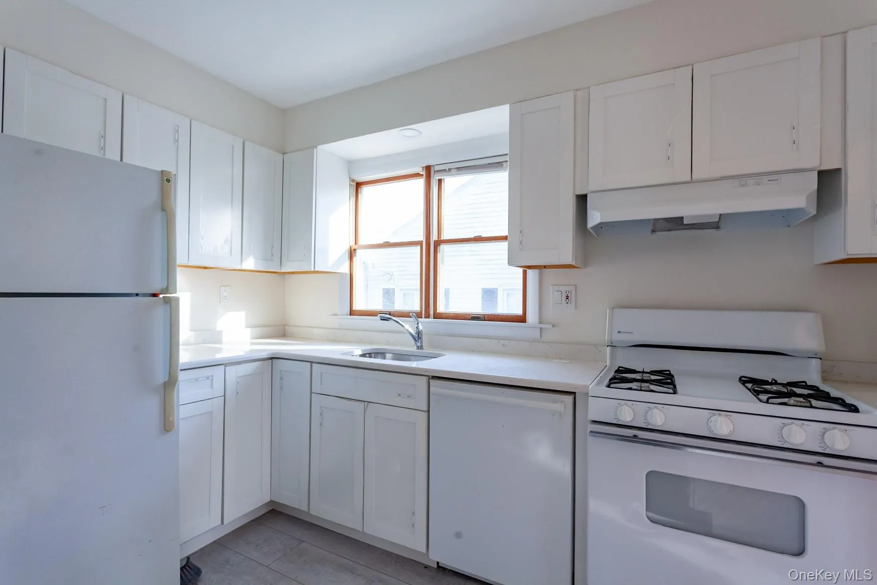 Kitchen with quartz countertops, white appliances and cabinets, and under cabinet range hood. Kitchen with quartz countertops, white appliances and cabinets, and under cabinet range hood.