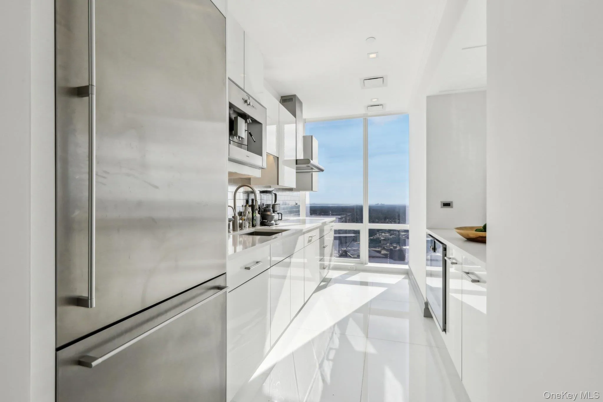 Kitchen with freestanding refrigerator, modern cabinets, floor to ceiling windows, and white cabinets Kitchen with freestanding refrigerator, modern cabinets, floor to ceiling windows, and white cabinets