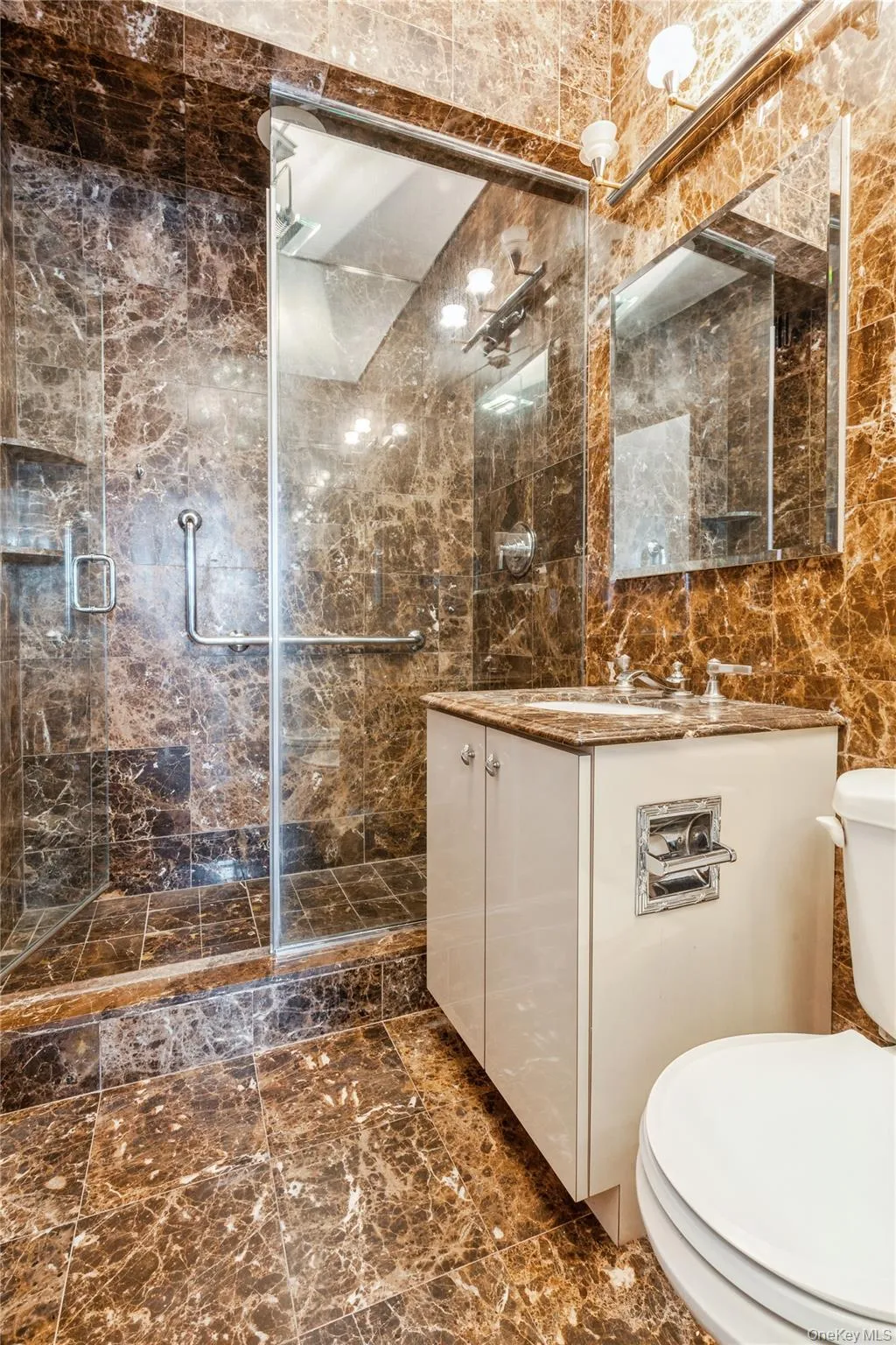 Full bathroom featuring vanity, a shower stall, tile walls, and marble finish floors Full bathroom featuring vanity, a shower stall, tile walls, and marble finish floors