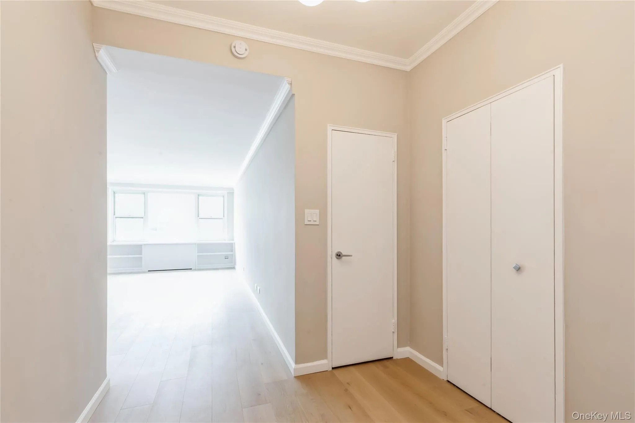 Hallway with crown molding and light wood-style floors Hallway with crown molding and light wood-style floors
