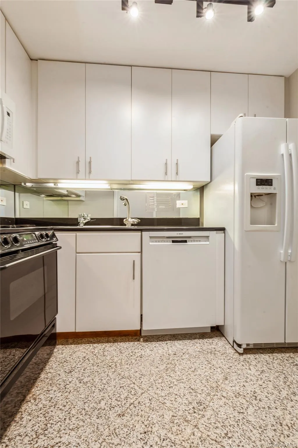 Kitchen with white appliances, white cabinets, and dark countertops Kitchen with white appliances, white cabinets, and dark countertops