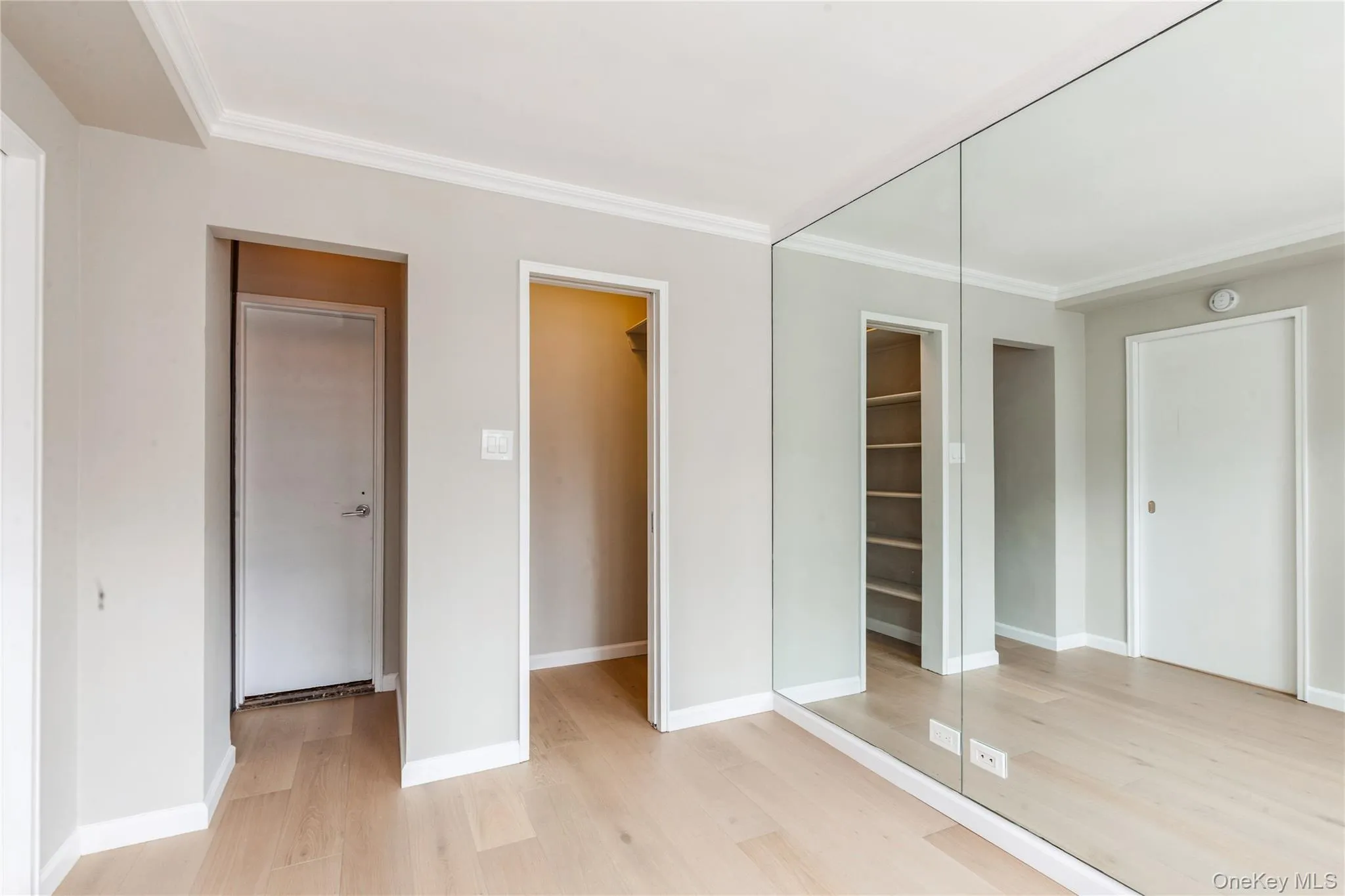 Unfurnished bedroom with light wood-type flooring, ornamental molding, and a closet Unfurnished bedroom with light wood-type flooring, ornamental molding, and a closet