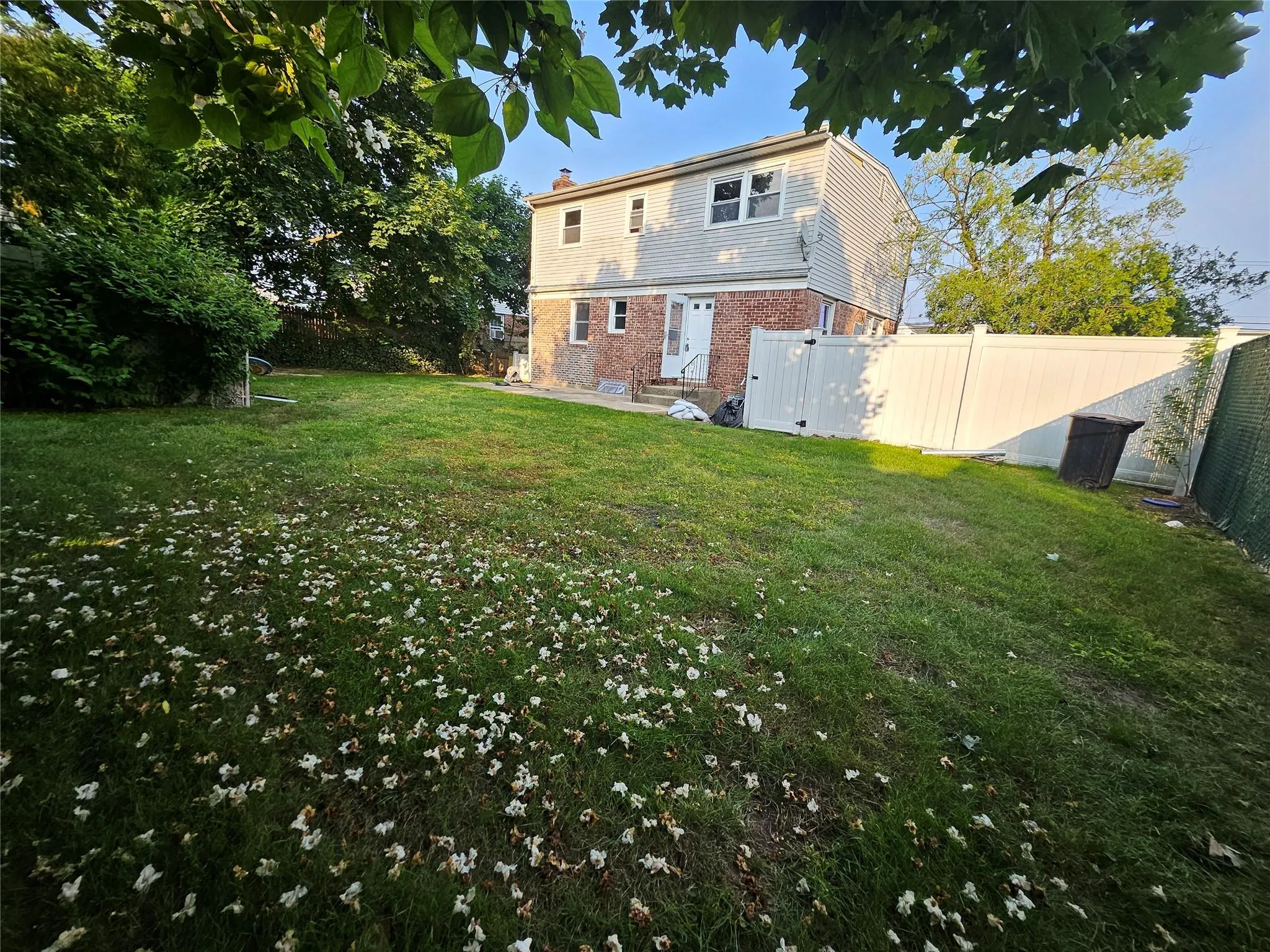 Rear view of house with brick siding, a fenced backyard, a chimney, and entry steps Rear view of house with brick siding, a fenced backyard, a chimney, and entry steps