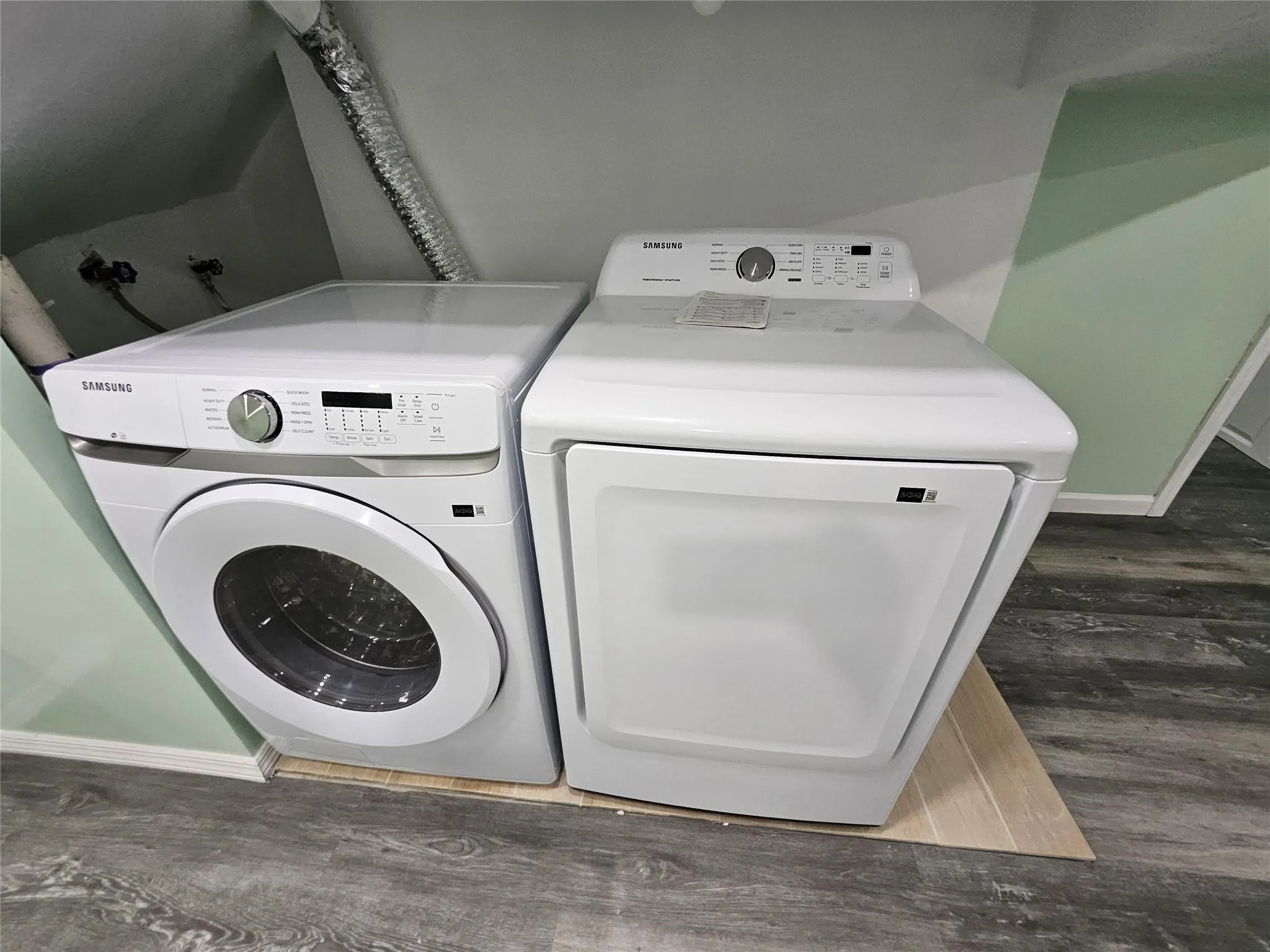 Laundry room featuring washer and clothes dryer and dark wood-type flooring Laundry room featuring washer and clothes dryer and dark wood-type flooring