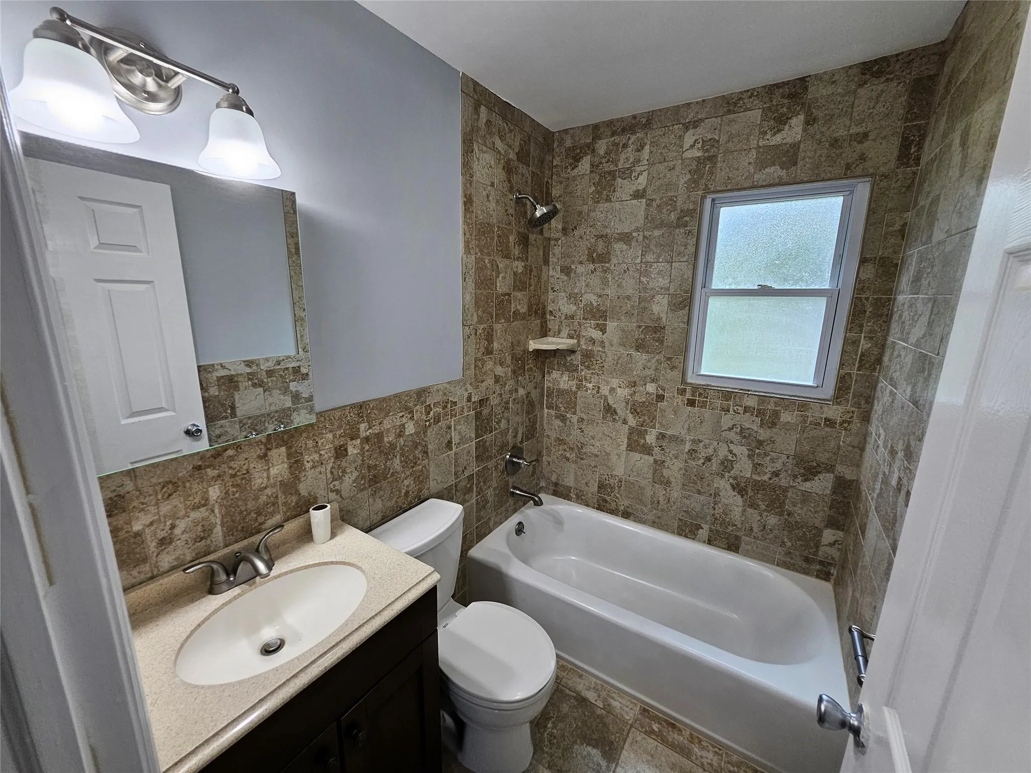 Full bathroom with washtub / shower combination, tile walls, and vanity Full bathroom with washtub / shower combination, tile walls, and vanity