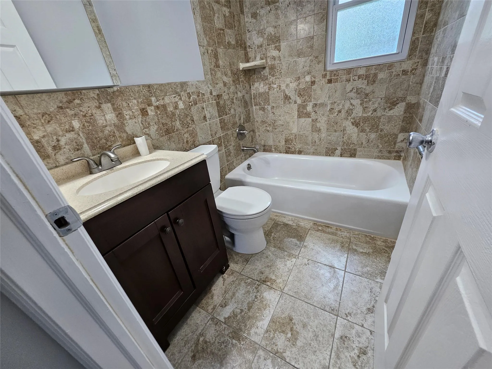 Full bath with vanity, shower / tub combination, and tile walls Full bath with vanity, shower / tub combination, and tile walls