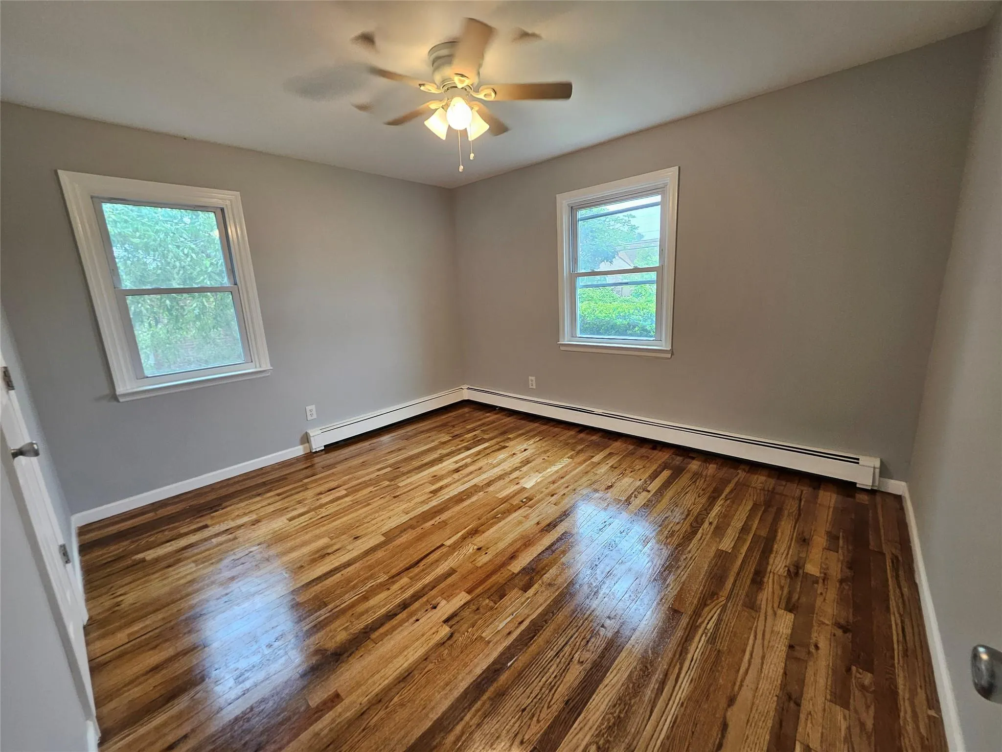 Spare room with hardwood / wood-style floors, ceiling fan, and baseboard heating Spare room with hardwood / wood-style floors, ceiling fan, and baseboard heating