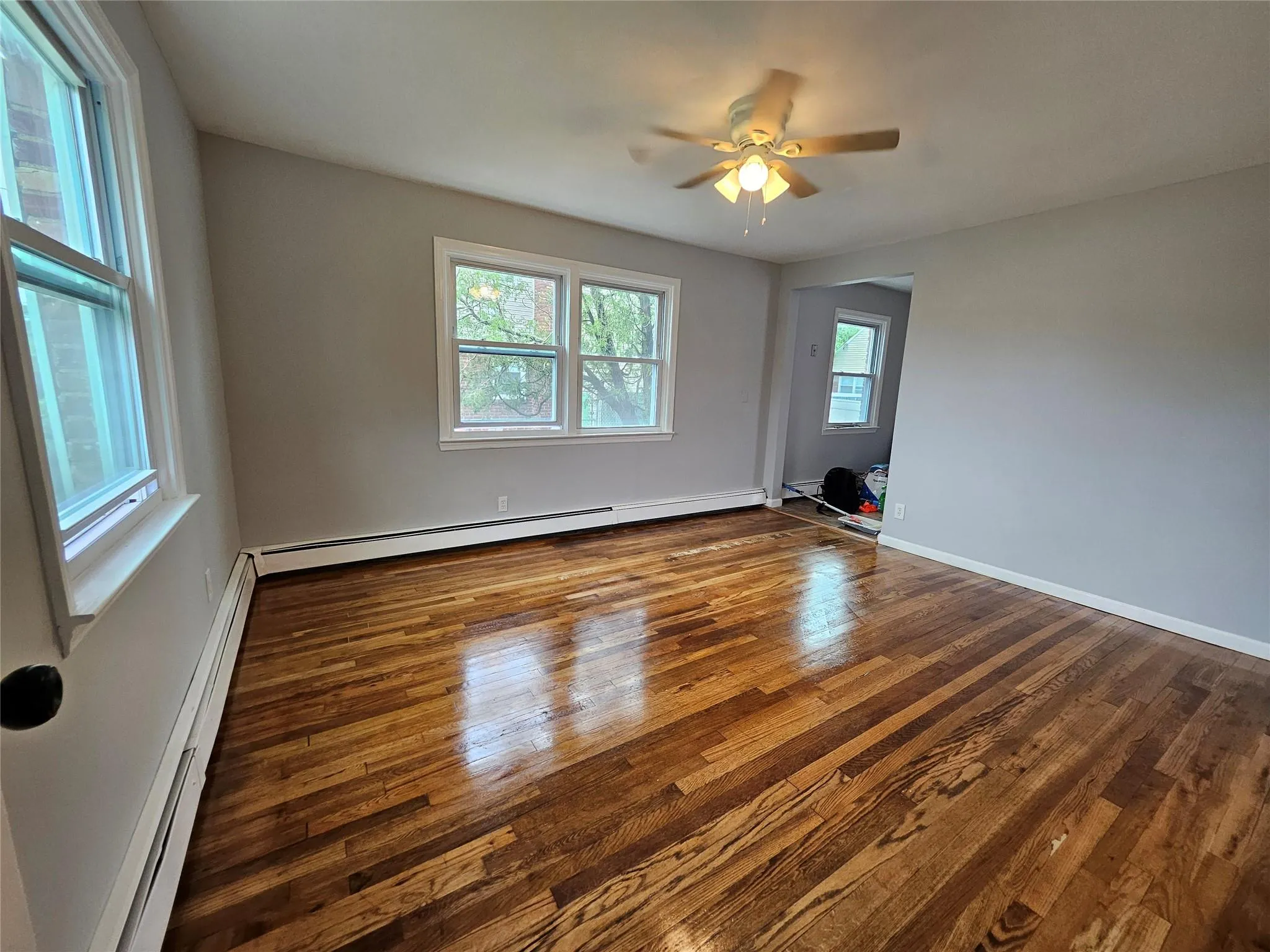 Unfurnished room with a baseboard radiator, dark wood-style floors, and ceiling fan Unfurnished room with a baseboard radiator, dark wood-style floors, and ceiling fan