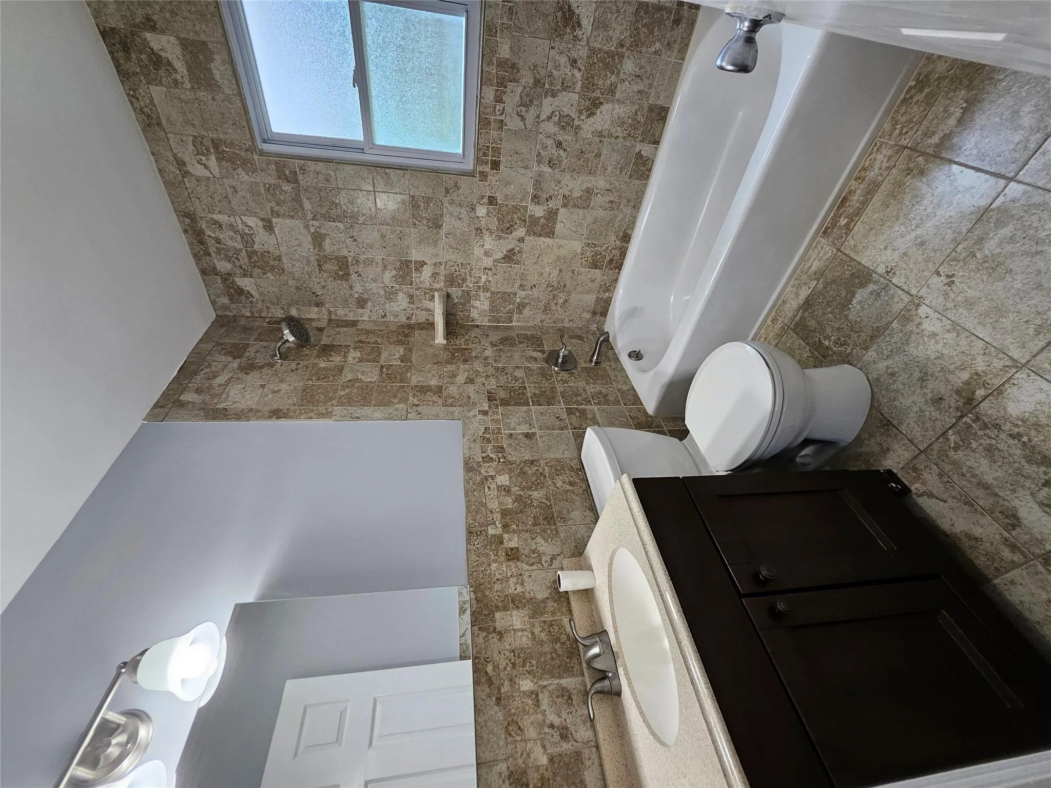 Bathroom with tub / shower combination, vanity, and tile walls Bathroom with tub / shower combination, vanity, and tile walls