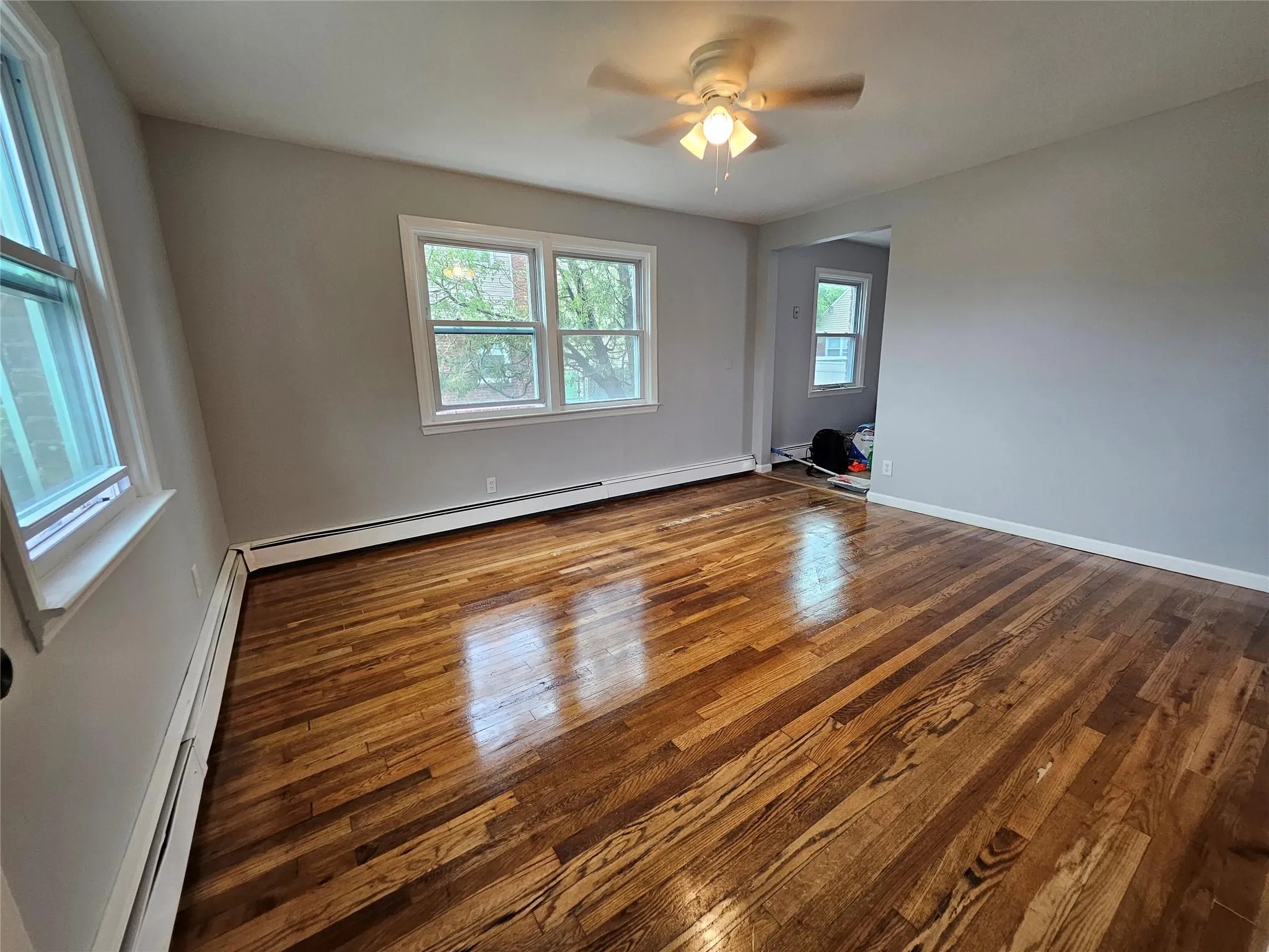 Spare room with a baseboard heating unit, dark wood-style floors, and ceiling fan Spare room with a baseboard heating unit, dark wood-style floors, and ceiling fan