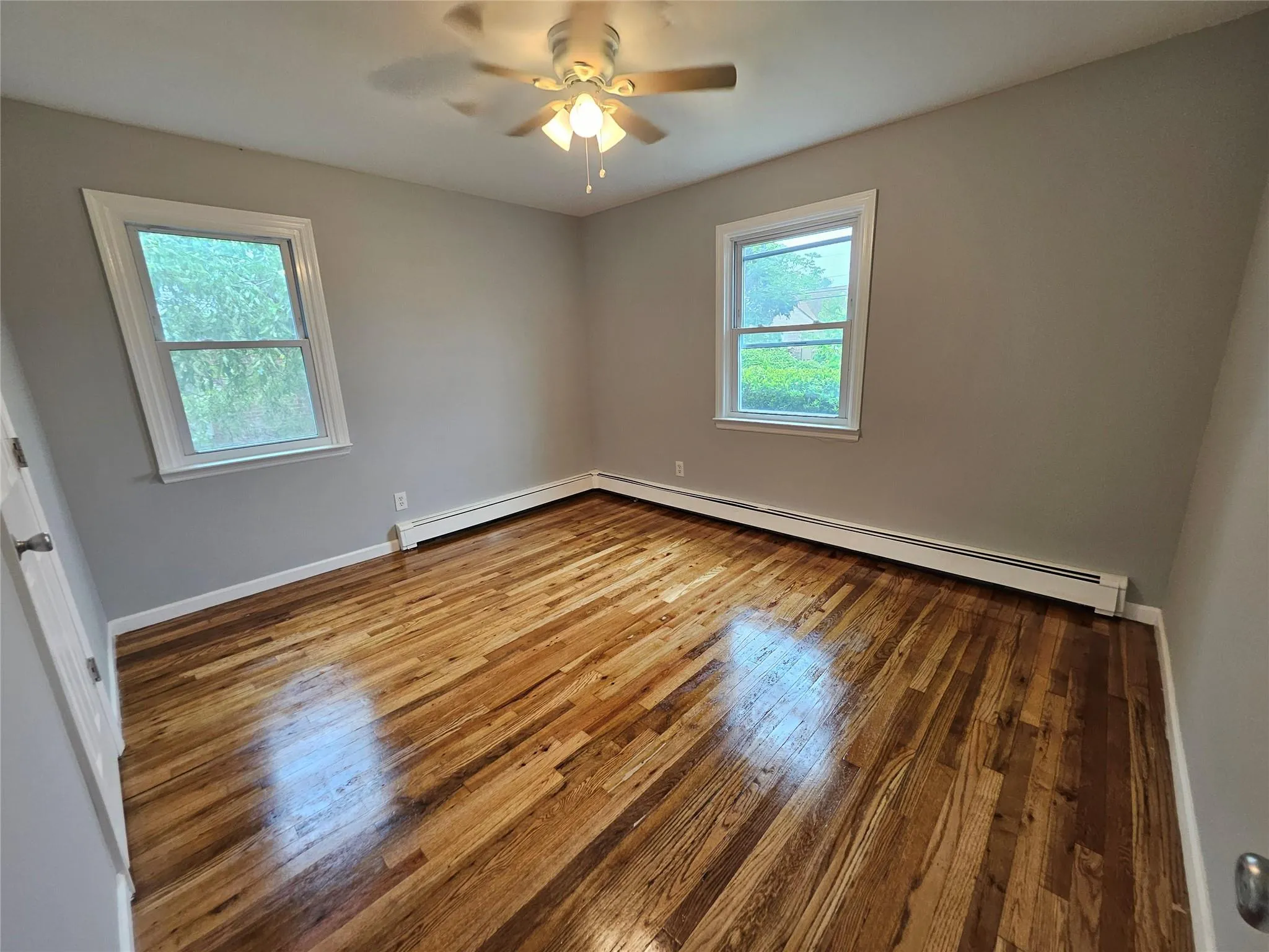 Unfurnished room featuring hardwood / wood-style floors, ceiling fan, and baseboard heating Unfurnished room featuring hardwood / wood-style floors, ceiling fan, and baseboard heating