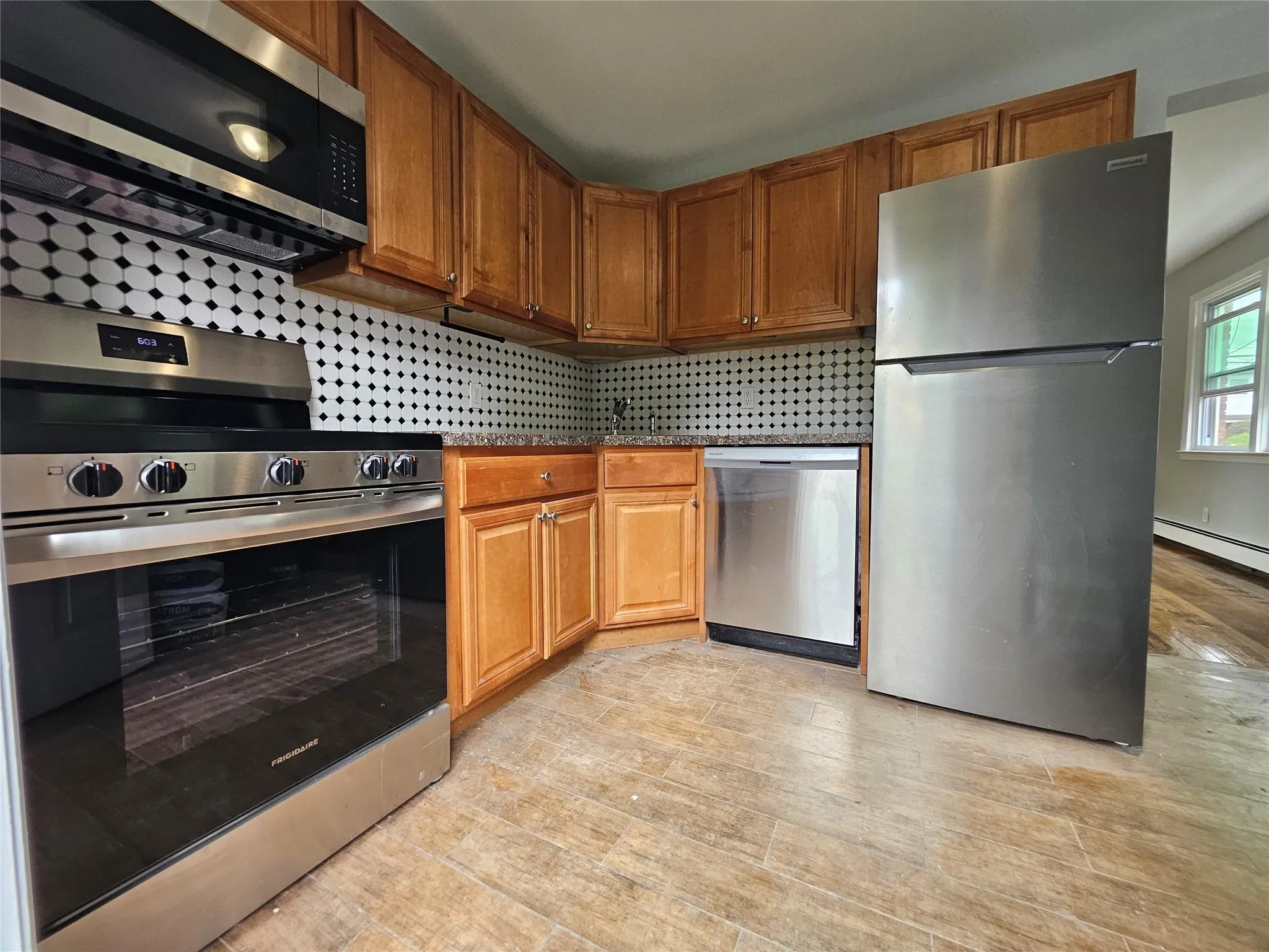 Kitchen featuring stainless steel appliances, tasteful backsplash, and brown cabinetry Kitchen featuring stainless steel appliances, tasteful backsplash, and brown cabinetry