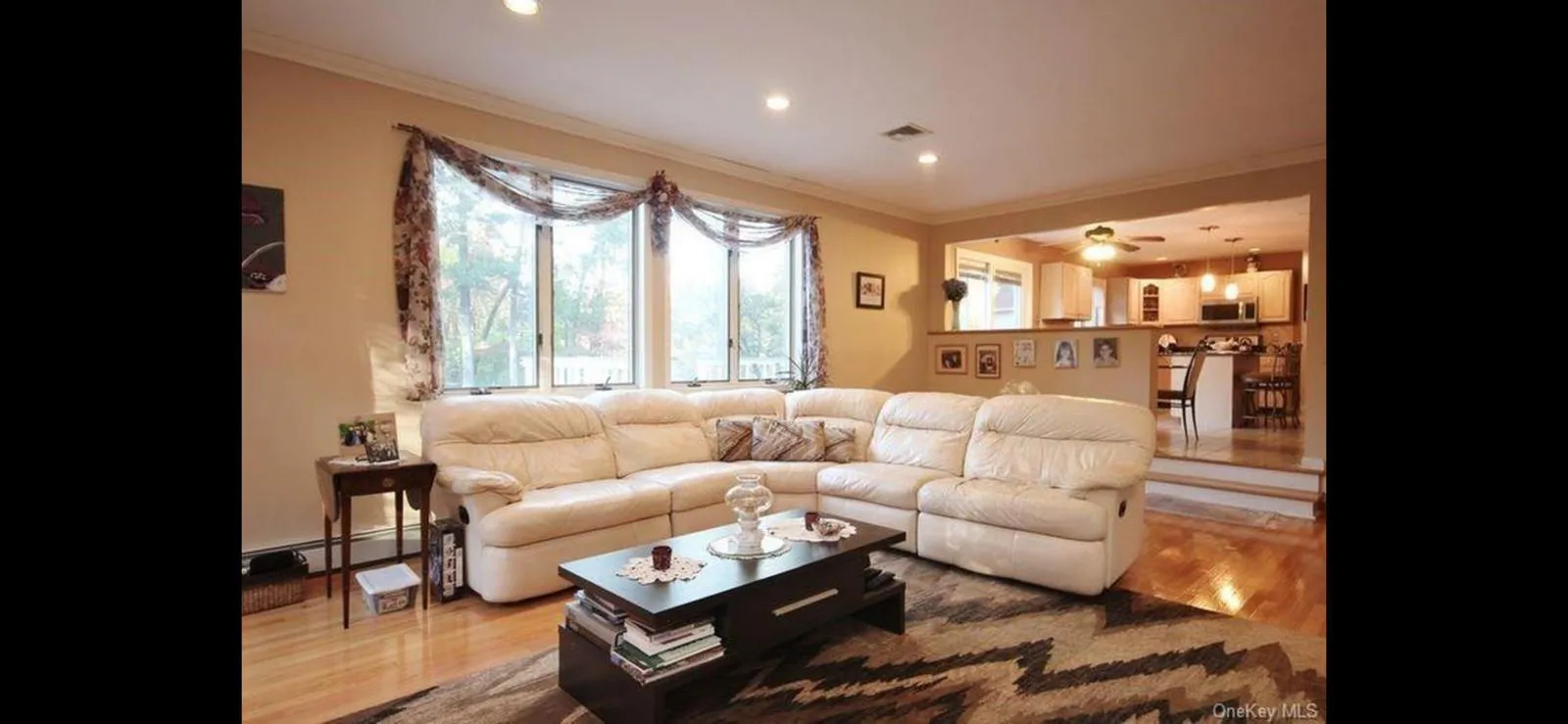 Living area featuring ornamental molding, wood finished floors, a baseboard heating unit, recessed lighting, and a ceiling fan Living area featuring ornamental molding, wood finished floors, a baseboard heating unit, recessed lighting, and a ceiling fan