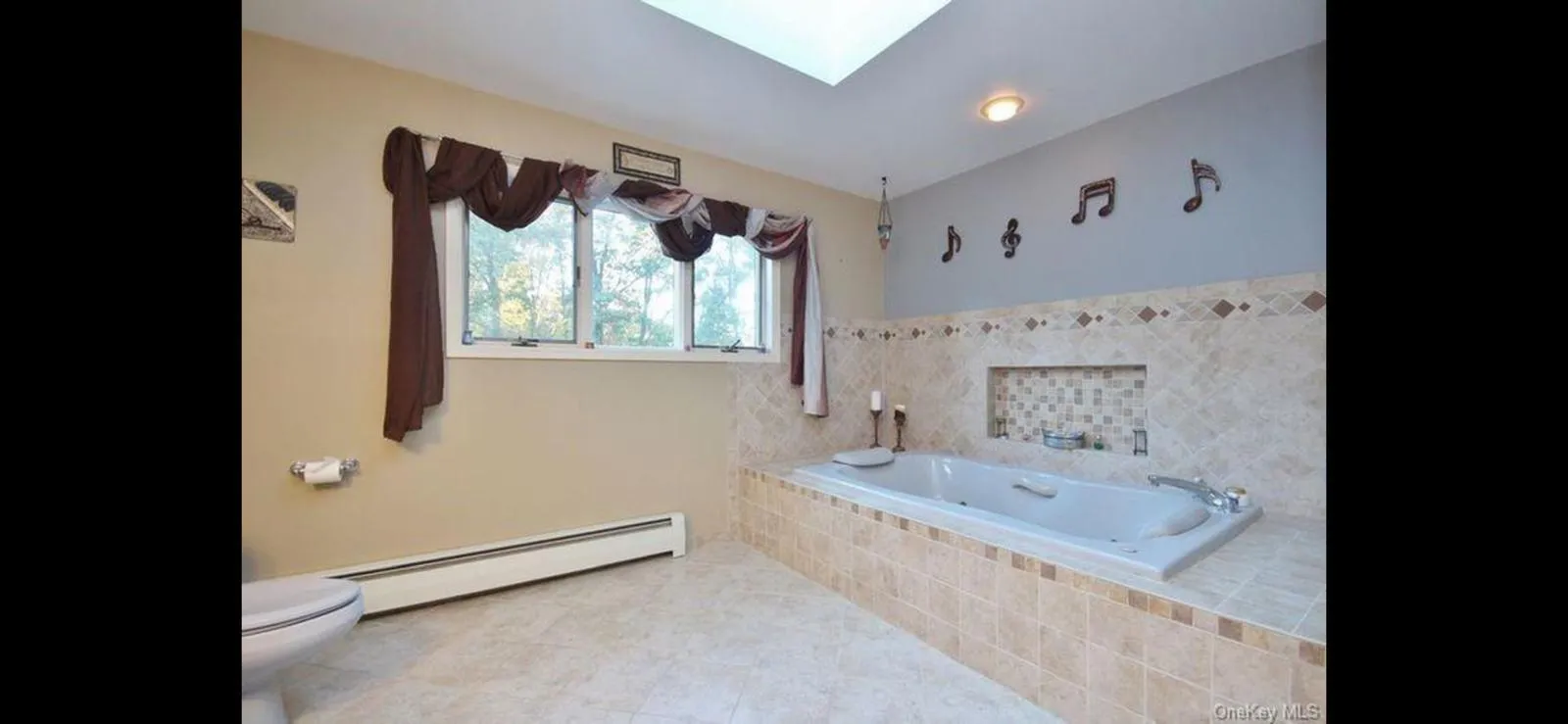 Bathroom with a baseboard heating unit, a bath, and a skylight Bathroom with a baseboard heating unit, a bath, and a skylight
