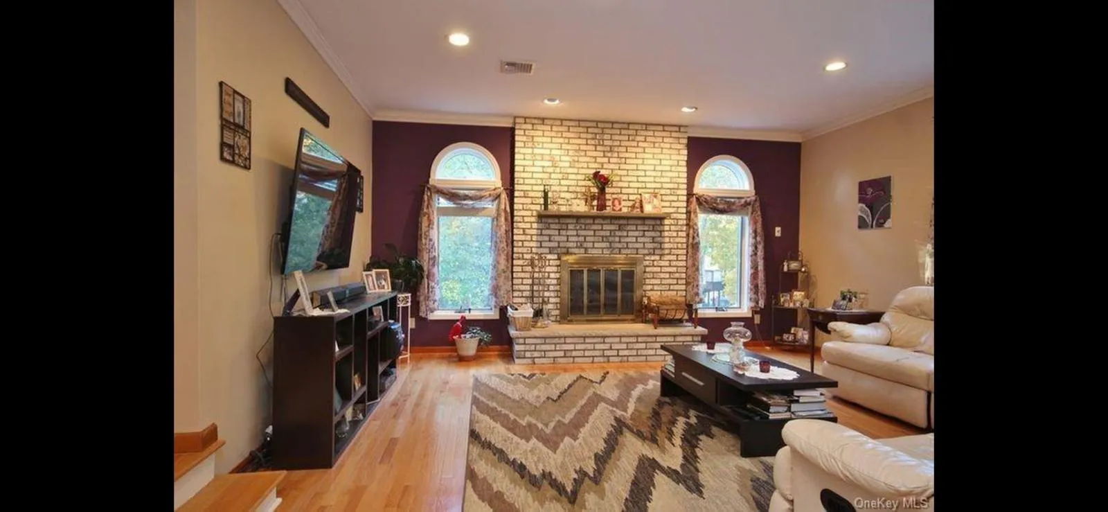 Living area featuring wood finished floors, crown molding, recessed lighting, and a brick fireplace Living area featuring wood finished floors, crown molding, recessed lighting, and a brick fireplace