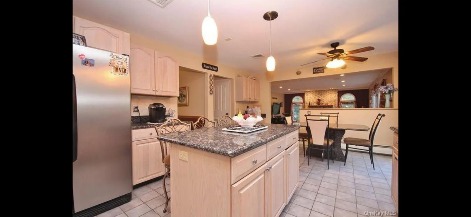 Kitchen featuring freestanding refrigerator, a center island, backsplash, a ceiling fan, and light tile patterned floors Kitchen featuring freestanding refrigerator, a center island, backsplash, a ceiling fan, and light tile patterned floors