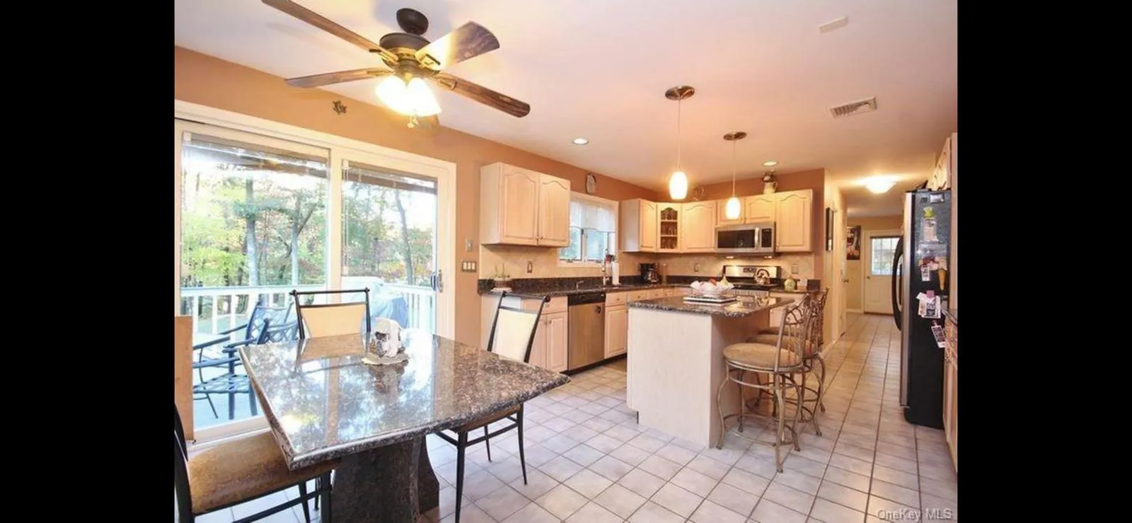Kitchen with stainless steel appliances, a breakfast bar, a center island, ceiling fan, and glass insert cabinets Kitchen with stainless steel appliances, a breakfast bar, a center island, ceiling fan, and glass insert cabinets