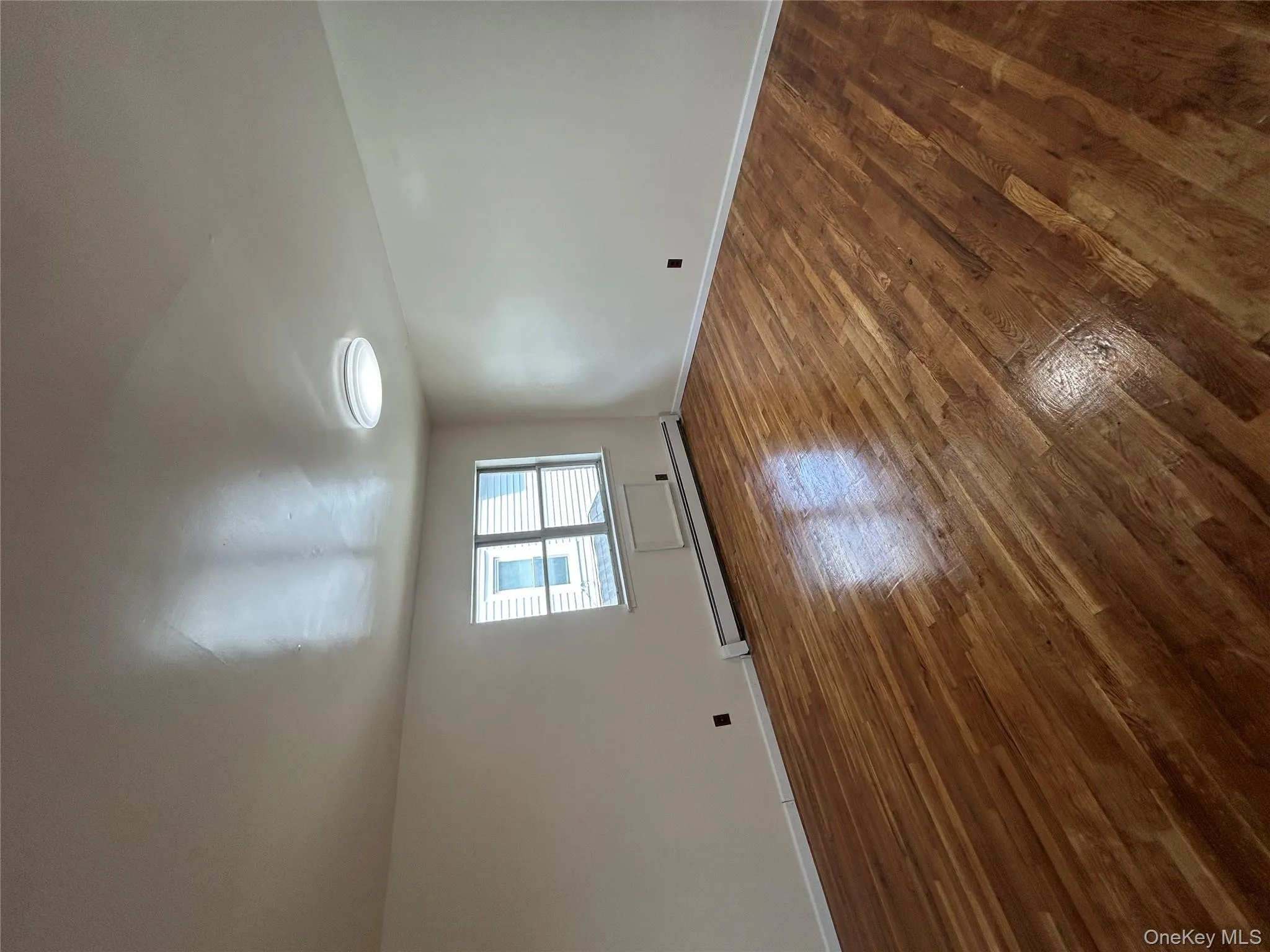 Spare room featuring a baseboard heating unit and dark wood-style floors Spare room featuring a baseboard heating unit and dark wood-style floors
