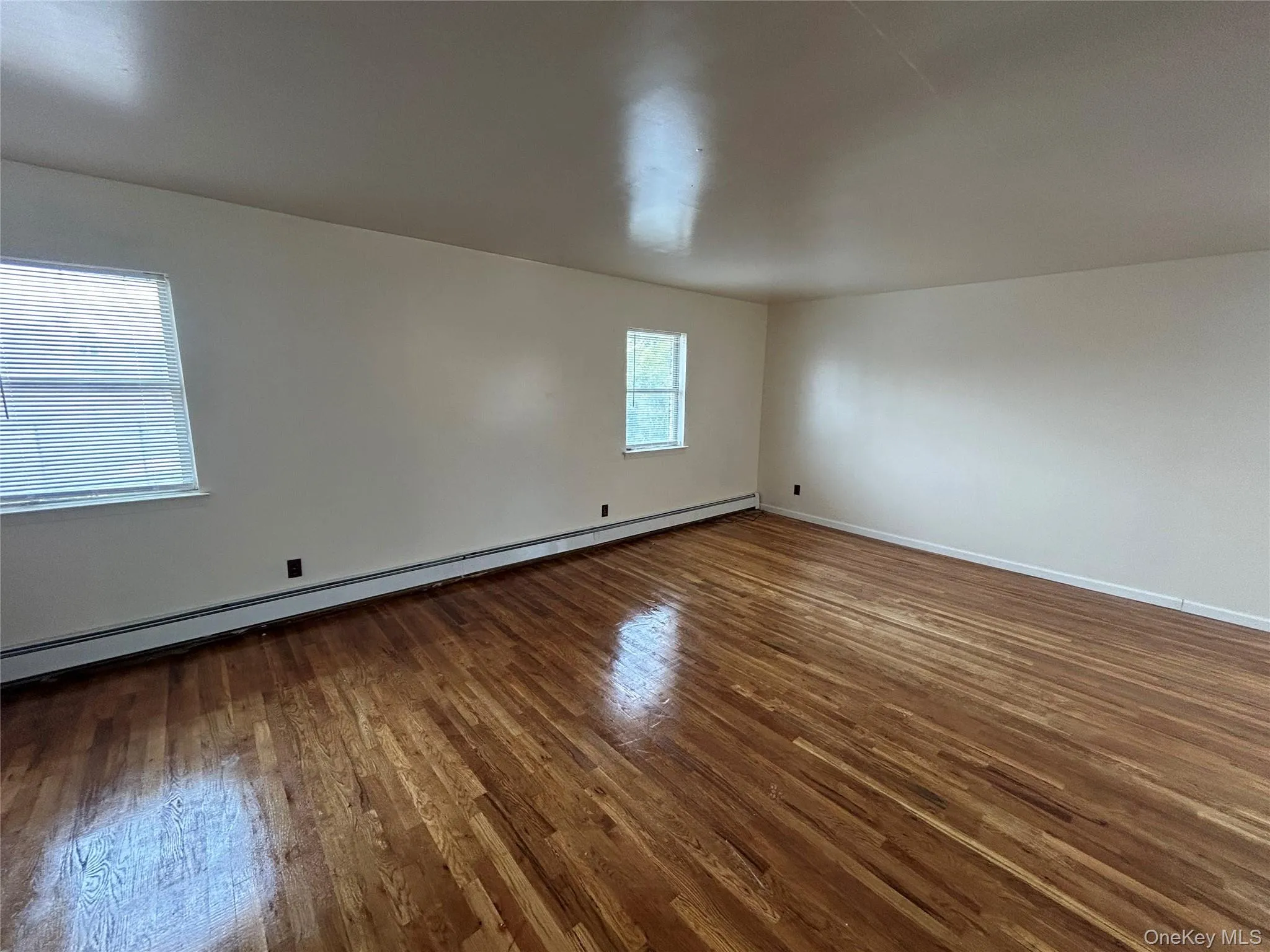 Spare room featuring a baseboard radiator and wood finished floors Spare room featuring a baseboard radiator and wood finished floors