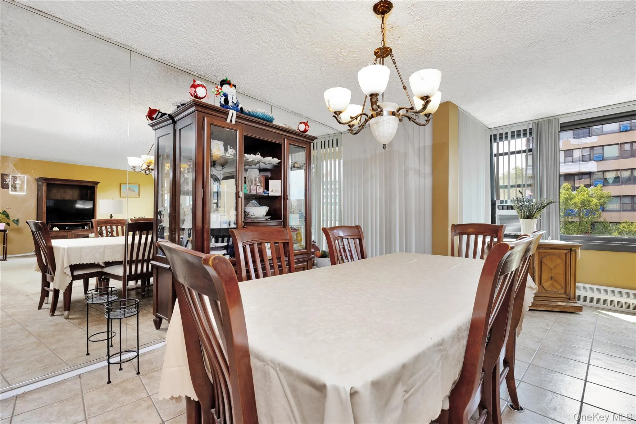 Dining space featuring a chandelier, light tile patterned floors, cooling unit, and a textured ceiling Dining space featuring a chandelier, light tile patterned floors, cooling unit, and a textured ceiling