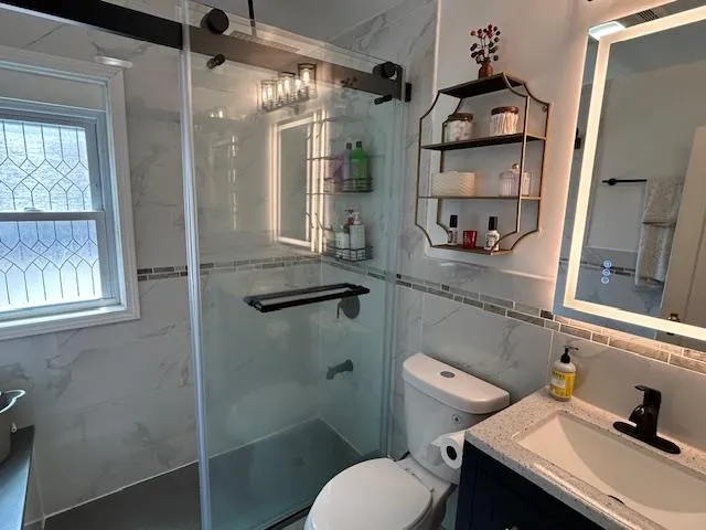 Full bath with vanity, a shower stall, and tile walls Full bath with vanity, a shower stall, and tile walls