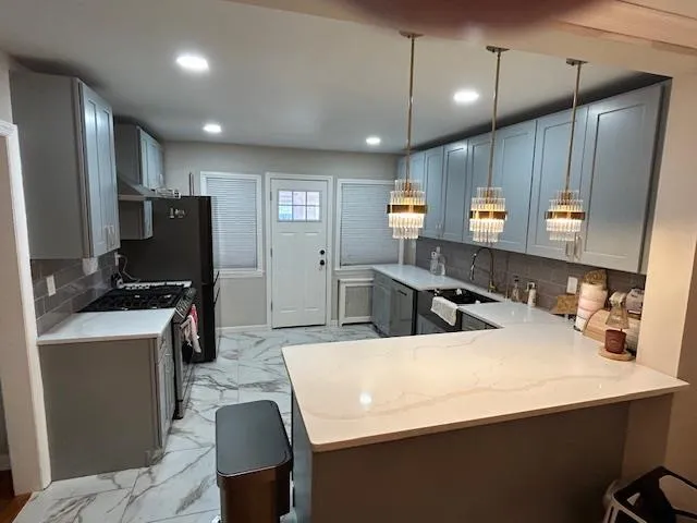 Kitchen with stainless steel range with gas cooktop, light marble finish floors, recessed lighting, range hood, and gray cabinetry Kitchen with stainless steel range with gas cooktop, light marble finish floors, recessed lighting, range hood, and gray cabinetry