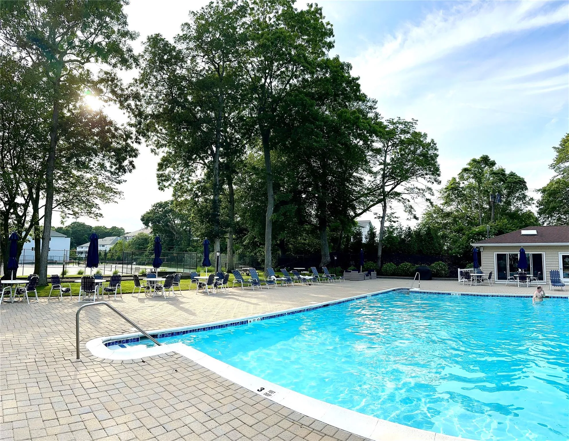 Community pool with a patio and view of wooded area Community pool with a patio and view of wooded area