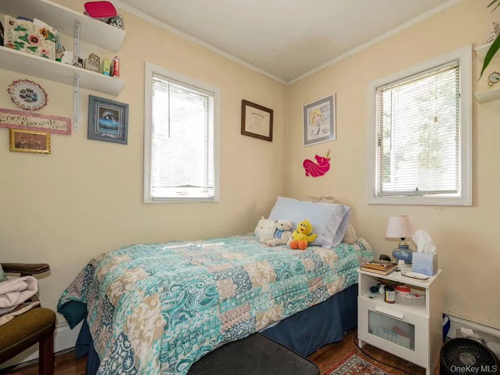 Bedroom featuring ornamental molding and wood finished floors Bedroom featuring ornamental molding and wood finished floors