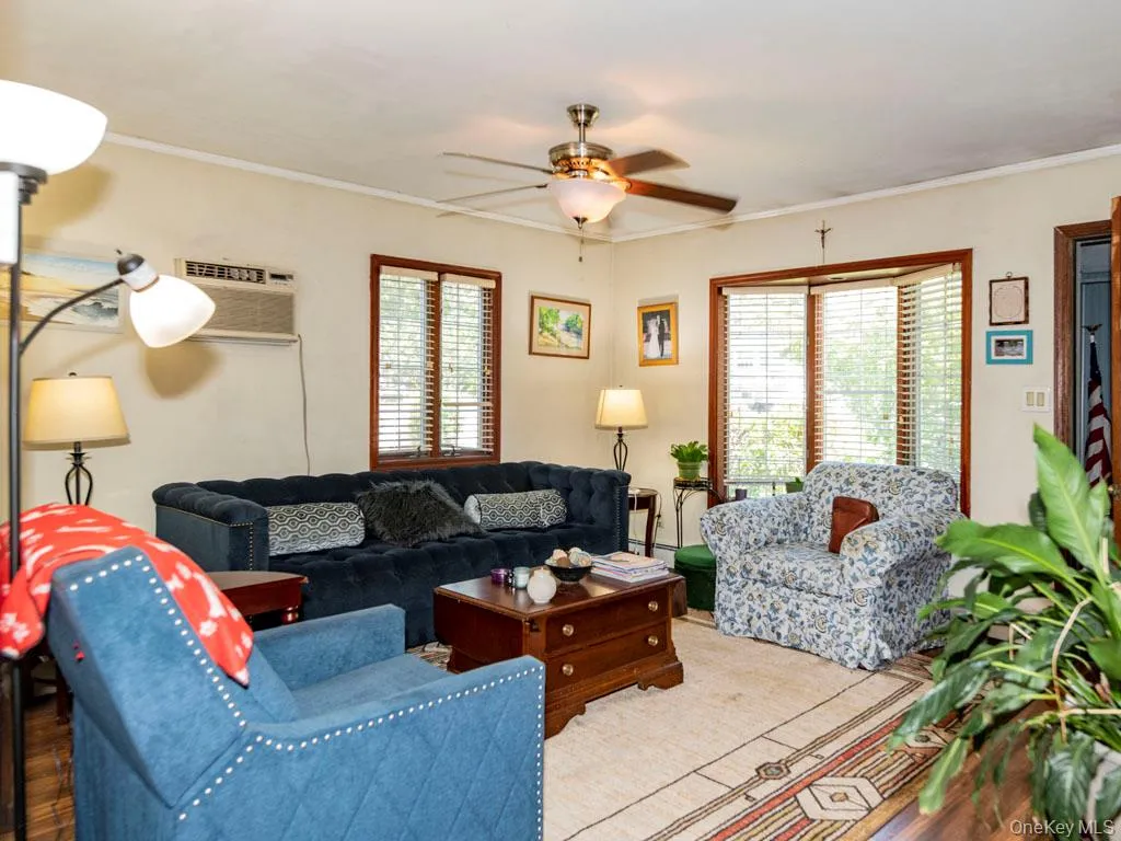 Living area with a ceiling fan, ornamental molding, wood finished floors, and an AC wall unit Living area with a ceiling fan, ornamental molding, wood finished floors, and an AC wall unit