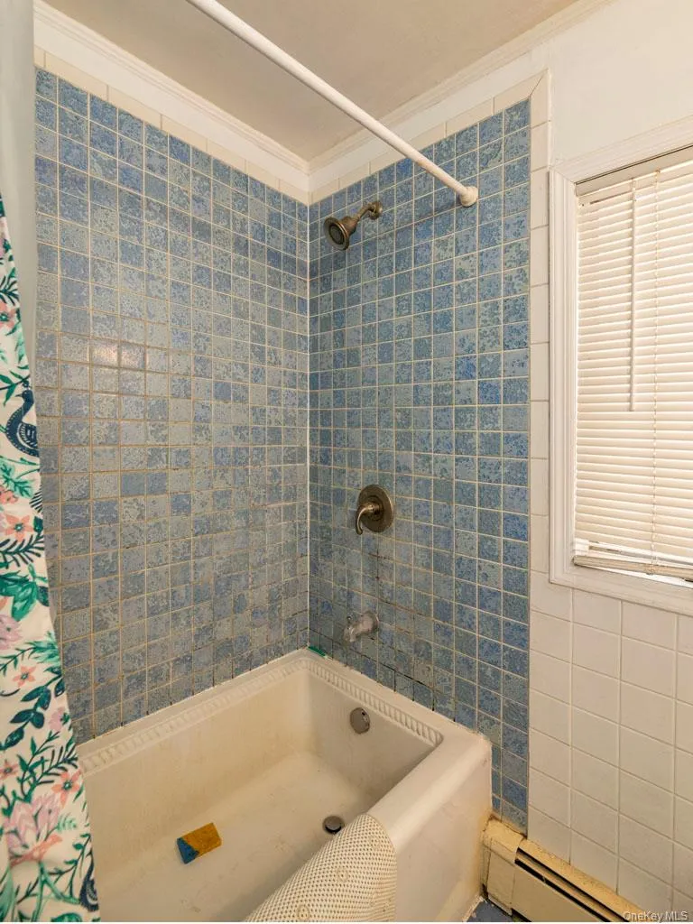 Bathroom featuring crown molding, baseboard heating, and shower / tub combo Bathroom featuring crown molding, baseboard heating, and shower / tub combo