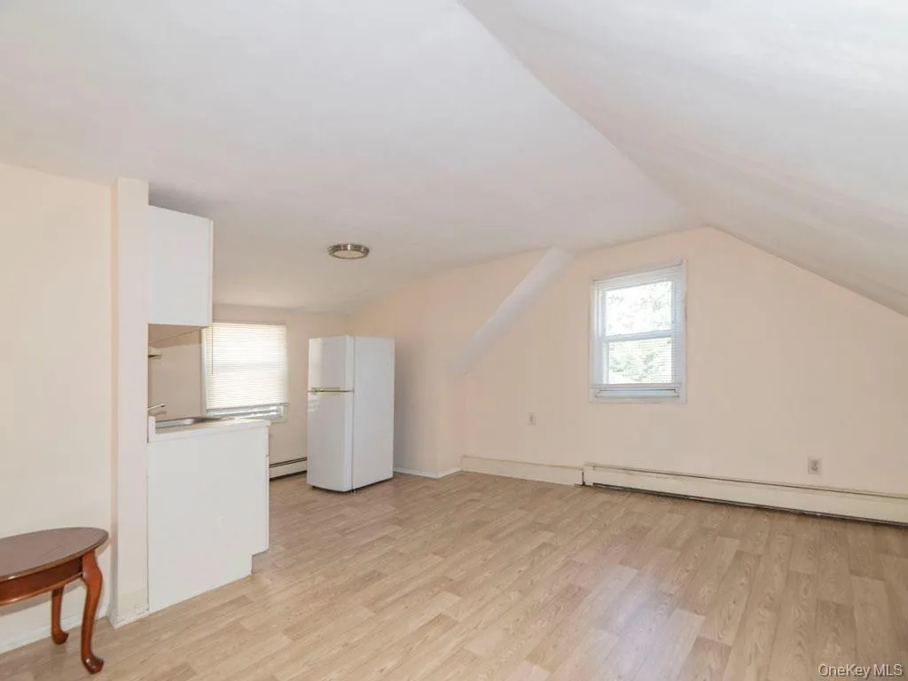Bonus room featuring light wood finished floors, vaulted ceiling, and a baseboard heating unit Bonus room featuring light wood finished floors, vaulted ceiling, and a baseboard heating unit