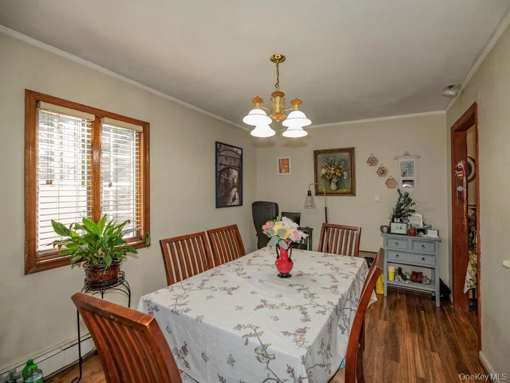 Dining area featuring a chandelier, baseboard heating, dark wood finished floors, and crown molding Dining area featuring a chandelier, baseboard heating, dark wood finished floors, and crown molding