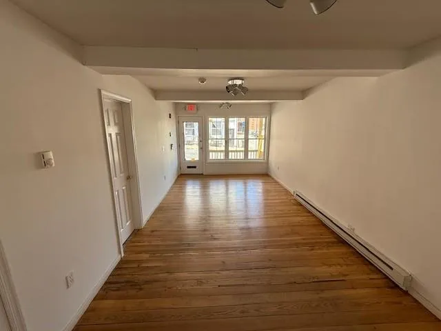 Spare room with a baseboard radiator and wood finished floors Spare room with a baseboard radiator and wood finished floors