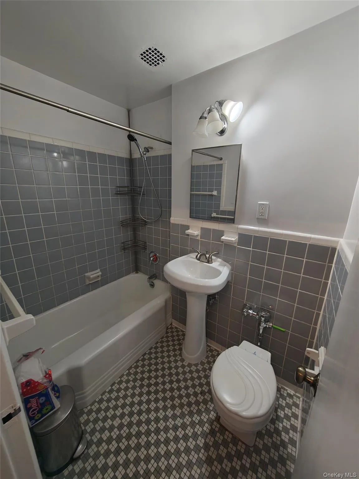 Full bath featuring shower / bathtub combination, tile walls, tile patterned flooring, and a wainscoted wall Full bath featuring shower / bathtub combination, tile walls, tile patterned flooring, and a wainscoted wall