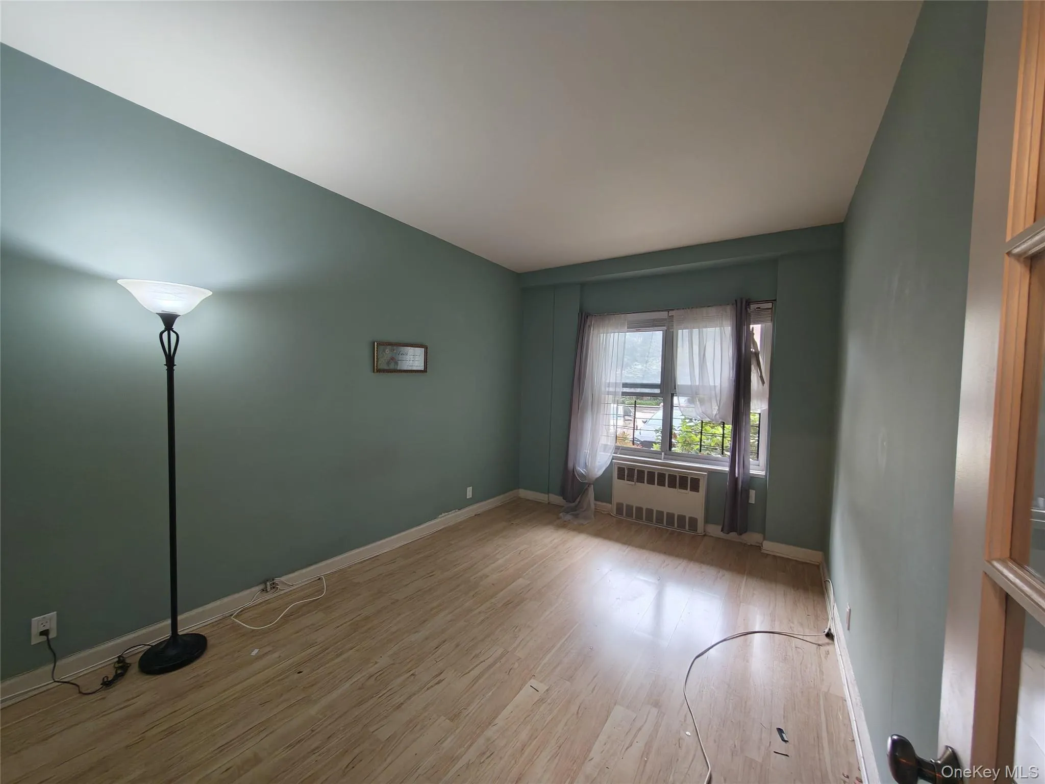 Spare room with wood finished floors and radiator heating unit Spare room with wood finished floors and radiator heating unit