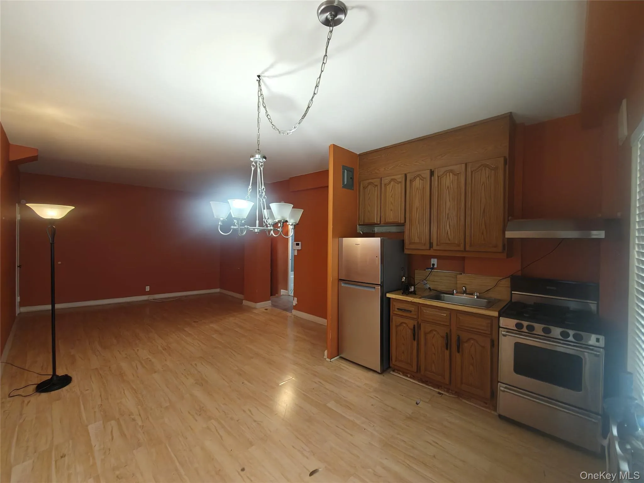 Kitchen with brown cabinetry, stainless steel appliances, light countertops, a chandelier, and light wood-type flooring Kitchen with brown cabinetry, stainless steel appliances, light countertops, a chandelier, and light wood-type flooring
