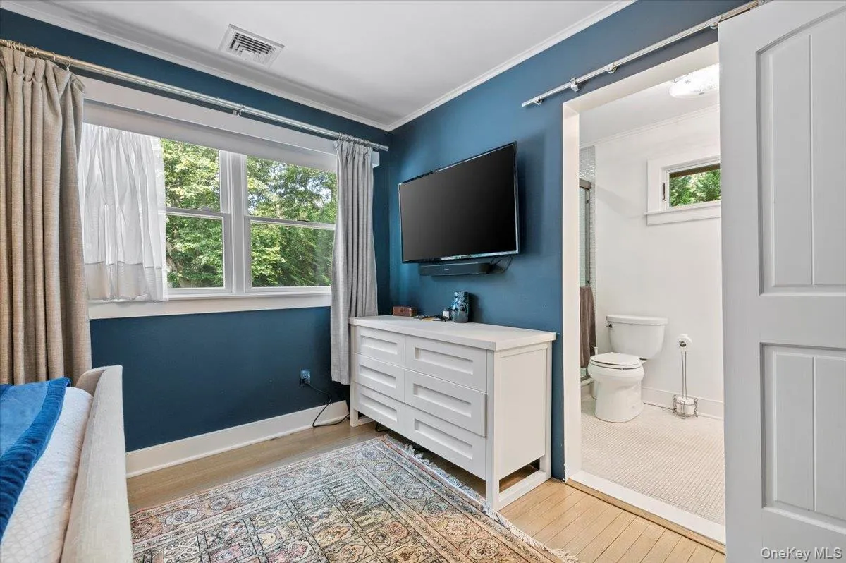 Bedroom featuring crown molding, light wood-type flooring, and connected bathroom Bedroom featuring crown molding, light wood-type flooring, and connected bathroom