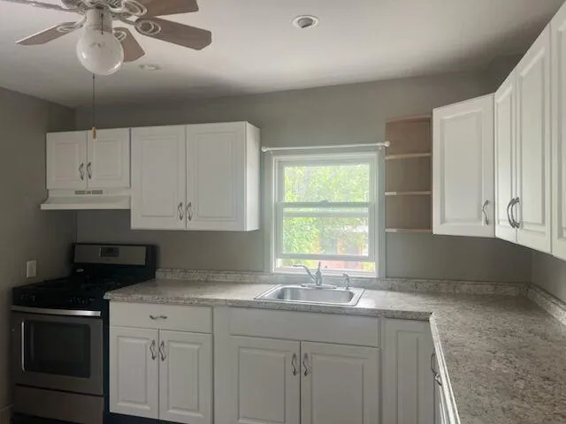 Kitchen with stainless steel gas range oven, white cabinetry, and light countertops Kitchen with stainless steel gas range oven, white cabinetry, and light countertops