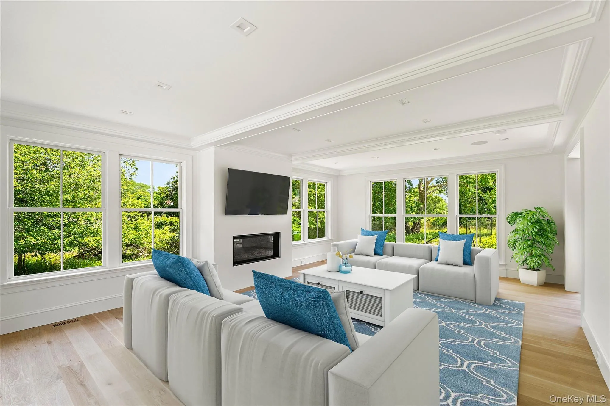 Living room featuring oak flooring, crown molding, and a glass covered gas fireplace Living room featuring oak flooring, crown molding, and a glass covered gas fireplace