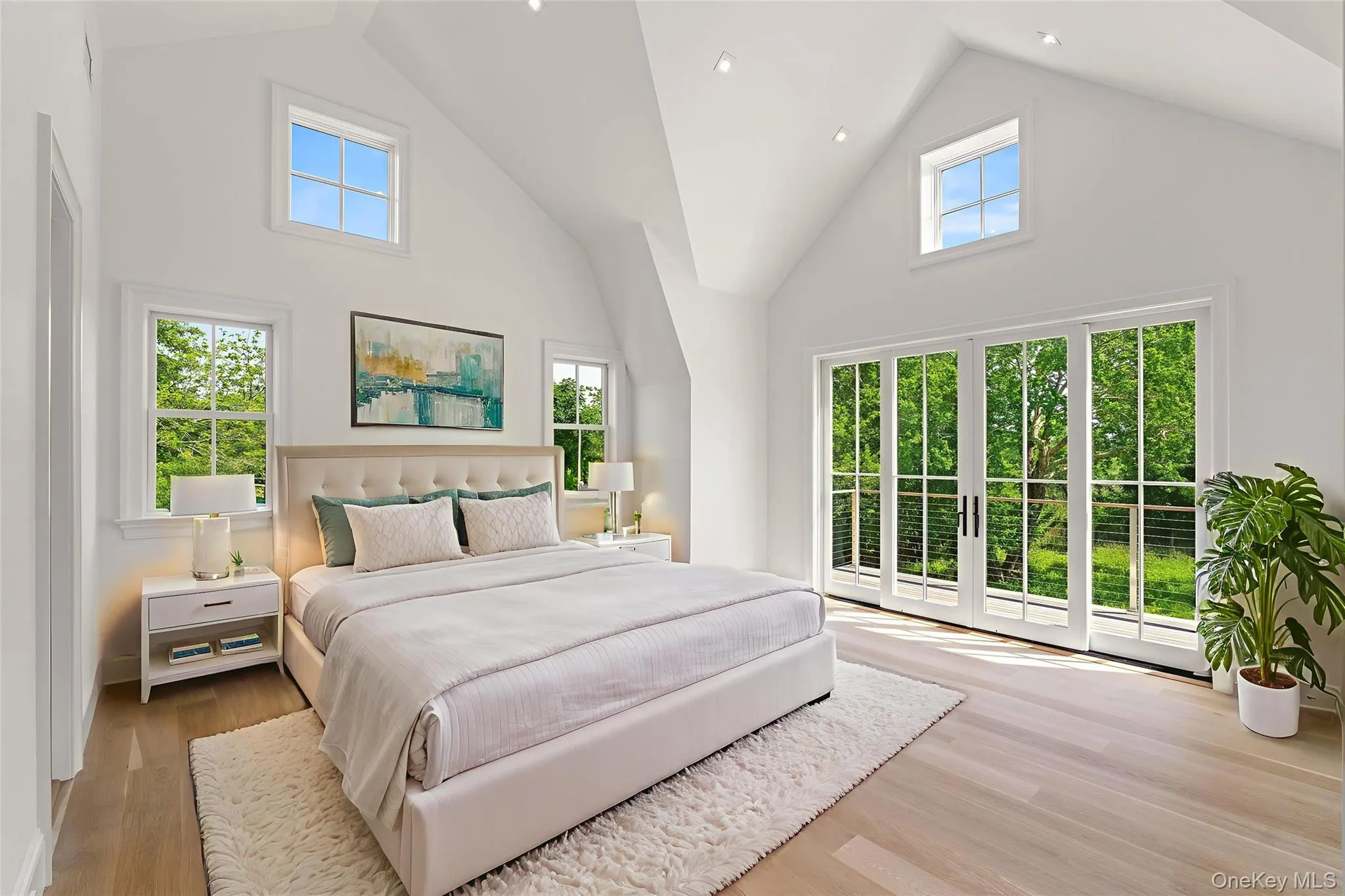Primary Bedroom featuring Cathedral ceilings, balcony, multiple windows, and wood finished floors Primary Bedroom featuring Cathedral ceilings, balcony, multiple windows, and wood finished floors