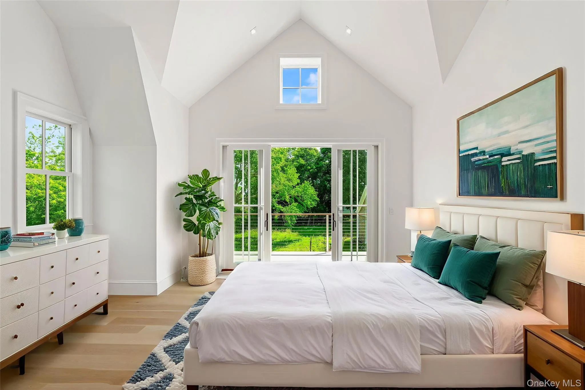 Bedroom featuring light wood finished floors and high vaulted ceiling Bedroom featuring light wood finished floors and high vaulted ceiling