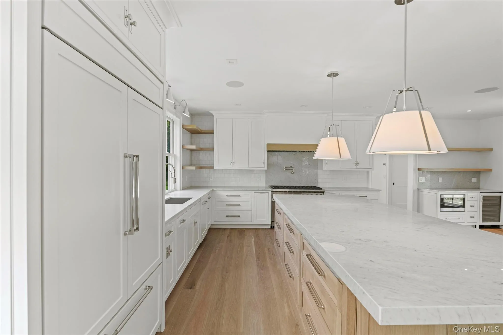 Kitchen with open shelves, stainless steel microwave, a large island, backsplash, and oak flooring- Kitchen close up Carrera Marble Kitchen with open shelves, stainless steel microwave, a large island, backsplash, and oak flooring- Kitchen close up Carrera Marble