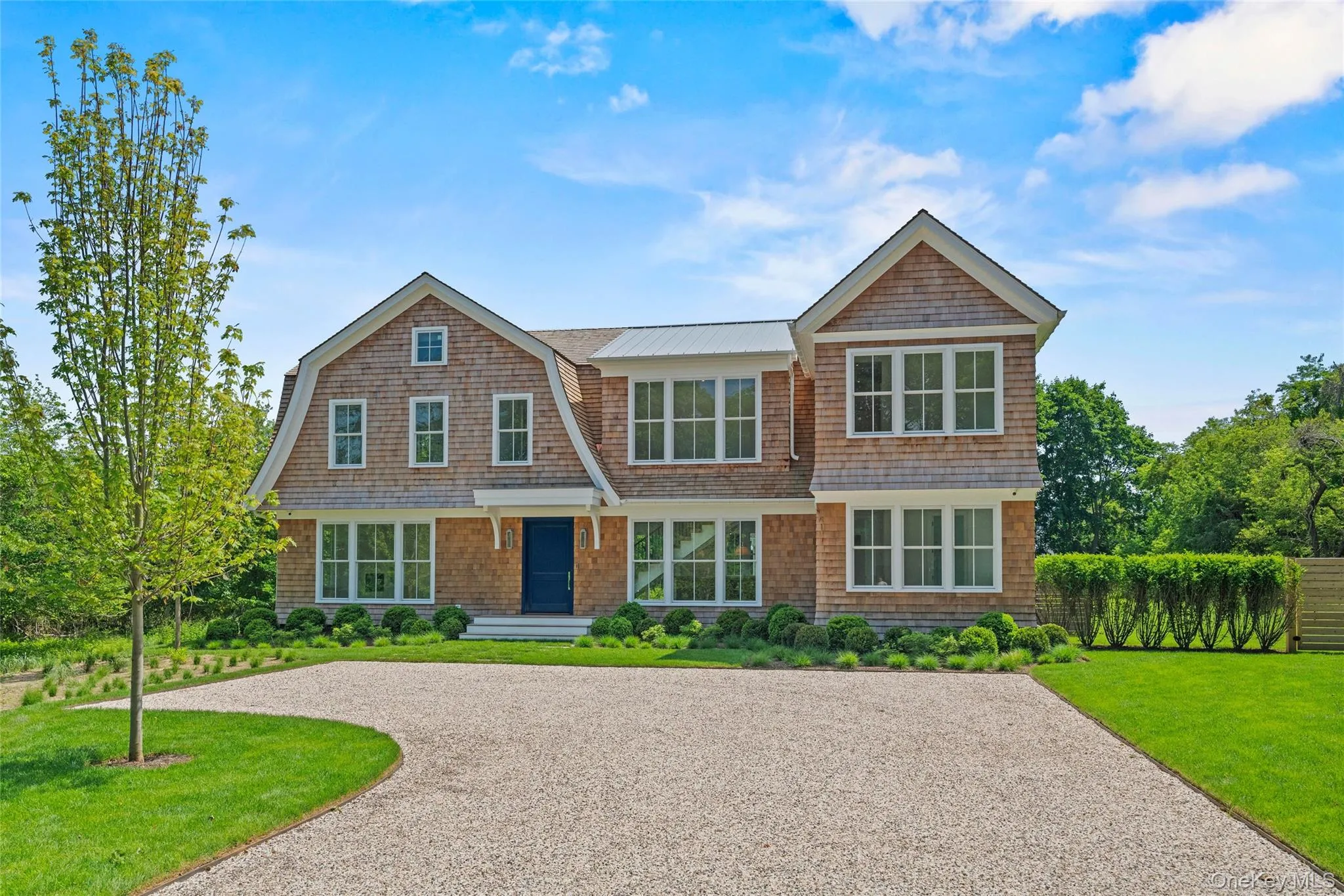 Daytime exterior showcasing the unique architectural design, distinctive Gambrel roofline, and timeless Hamptons elegance of this extraordinary new waterfront residence. Daytime exterior showcasing the unique architectural design, distinctive Gambrel roofline, and timeless Hamptons elegance of this extraordinary new waterfront residence.