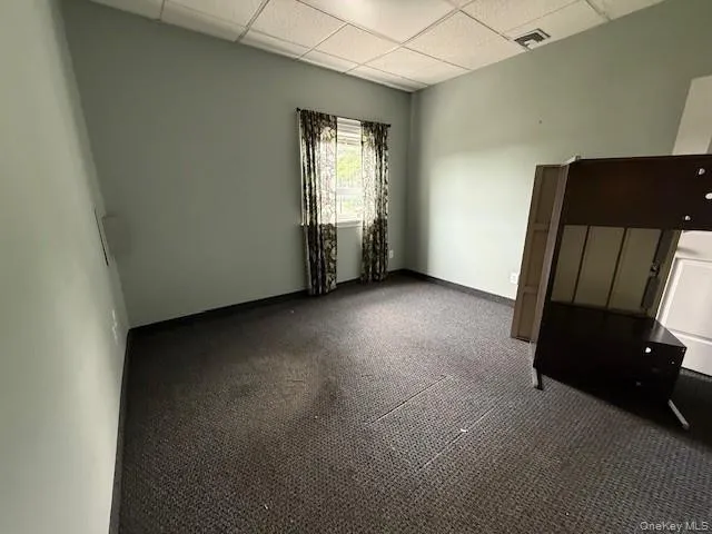 Empty room featuring a drop ceiling and carpet floors Empty room featuring a drop ceiling and carpet floors