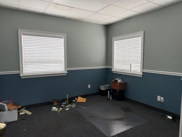 Carpeted empty room with healthy amount of natural light and a drop ceiling Carpeted empty room with healthy amount of natural light and a drop ceiling