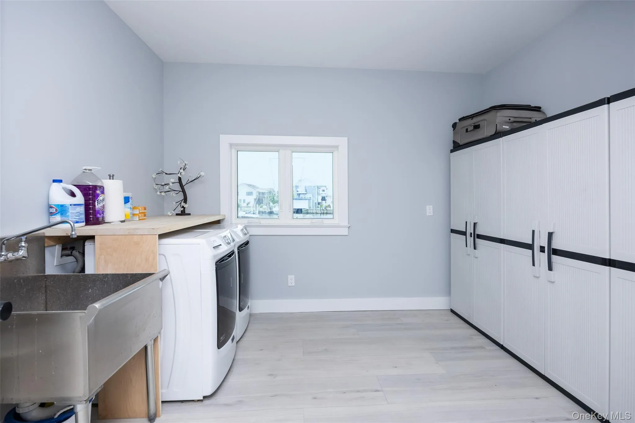 Laundry room with independent washer and dryer, light wood-style flooring, and cabinet space Laundry room with independent washer and dryer, light wood-style flooring, and cabinet space